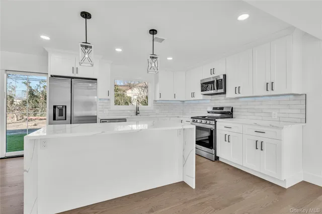 a kitchen with kitchen island white cabinets and stainless steel appliances