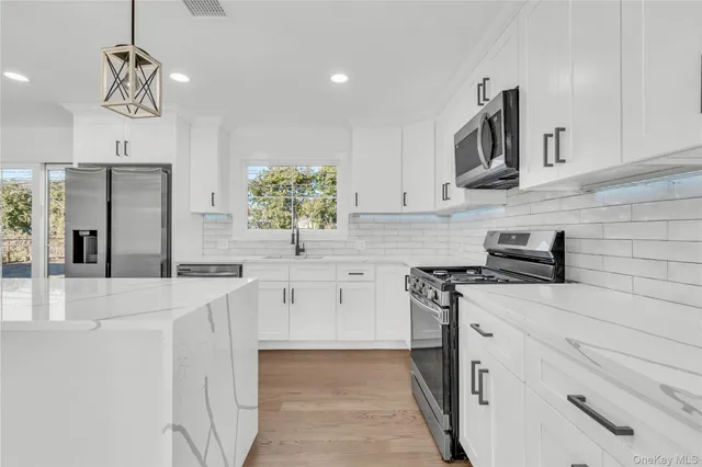 a kitchen with stainless steel appliances granite countertop a sink a stove and a refrigerator