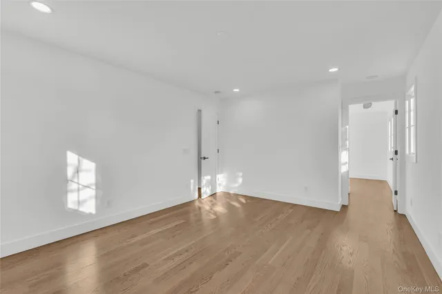 a view of empty room with wooden floor and window