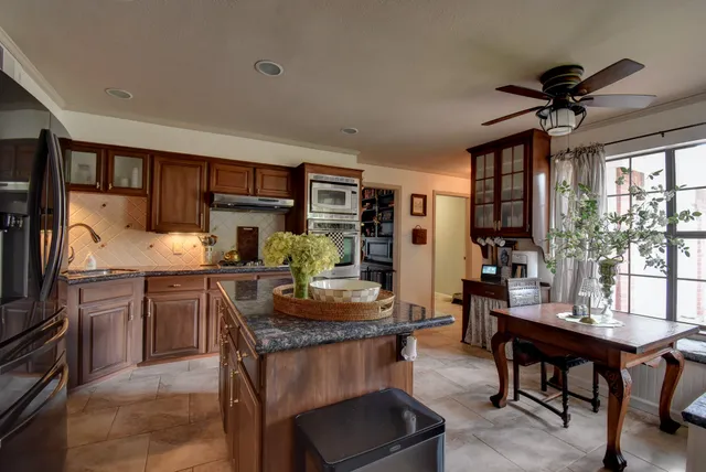 a kitchen with granite countertop a table chairs microwave and cabinets