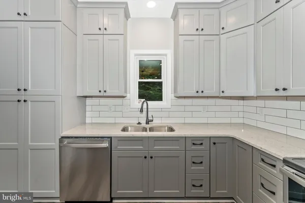 a kitchen with white cabinets and sink