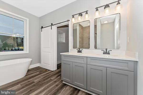 a bathroom with a double vanity sink mirror and bathtub