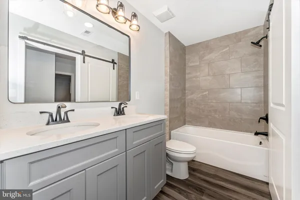 a bathroom with a double vanity sink toilet mirror and bathtub
