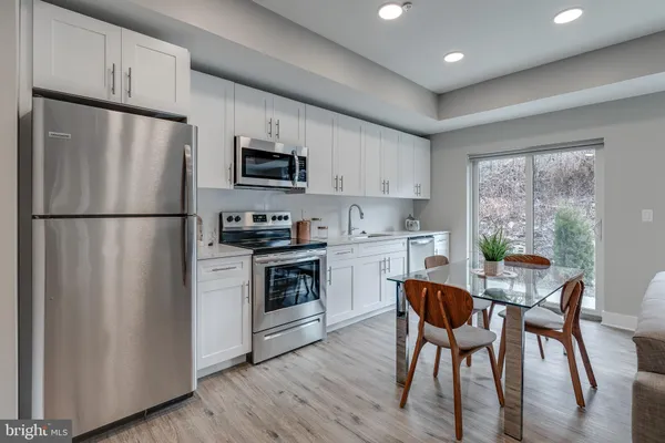 a kitchen with stainless steel appliances a refrigerator a stove a sink a dining table and chairs