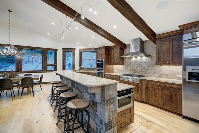 a kitchen with stainless steel appliances granite countertop a table chairs sink and wooden cabinets
