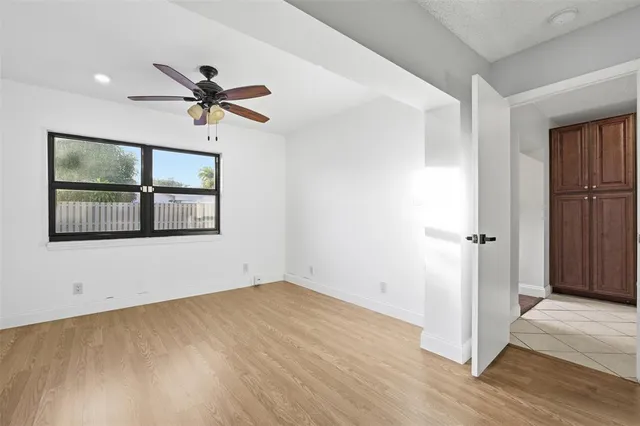 a view of empty room with wooden floor and ceiling fan