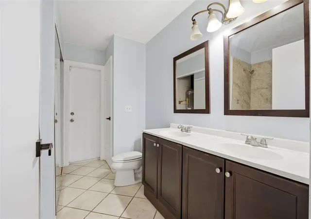 a bathroom with a double vanity sink mirror and toilet