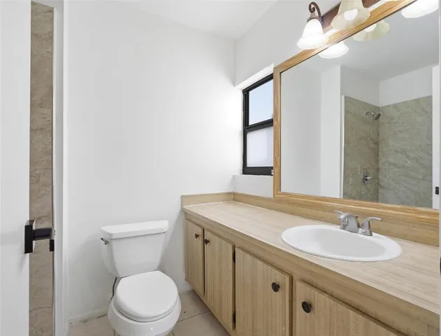 a bathroom with a granite countertop sink a toilet and a mirror