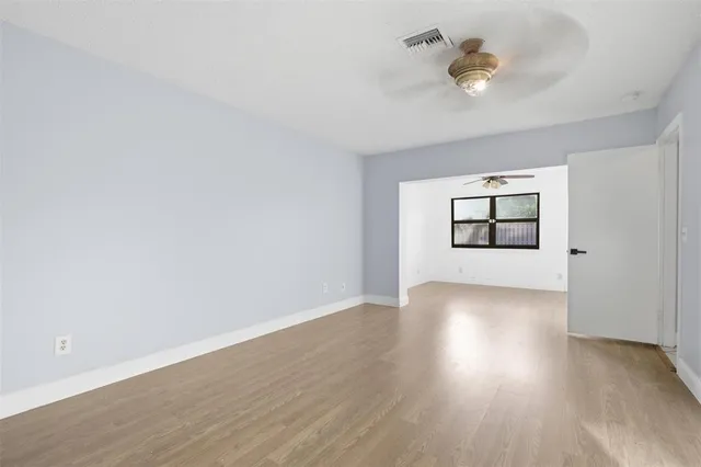 an empty room with wooden floor and windows