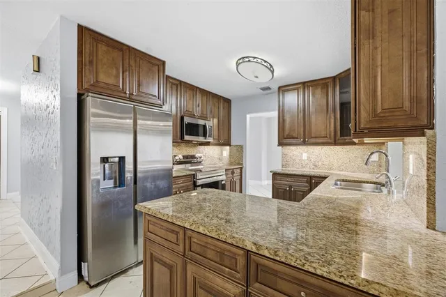 a kitchen with stainless steel appliances granite countertop a refrigerator a stove and a sink with wooden floor