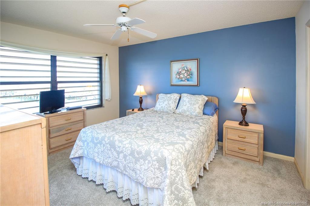 4540 Northeast Sandpebble Trace, Unit 302 Stuart, FL 34996 - Photo 15 of 34 a bedroom with a bed and a lamp