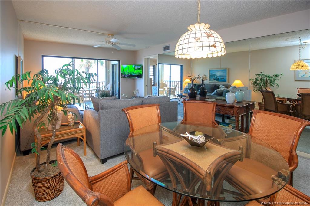 4540 Northeast Sandpebble Trace, Unit 302 Stuart, FL 34996 - Photo 9 of 34 a dining room with furniture a large window and a chandelier
