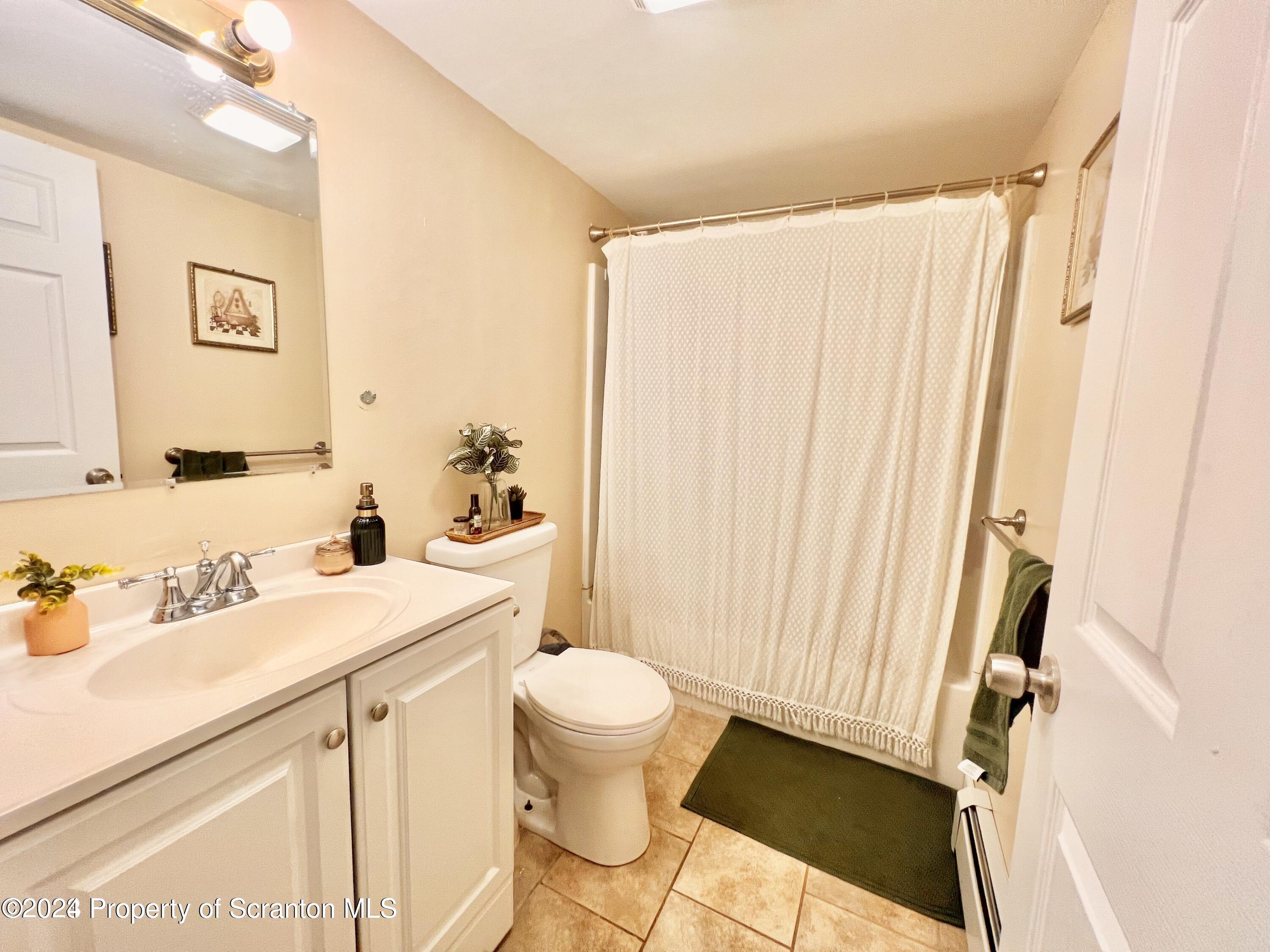 721 Columbia Street, Unit A Scranton, PA 18509 - Photo 5 of 12 a bathroom with a sink a toilet and shower curtain