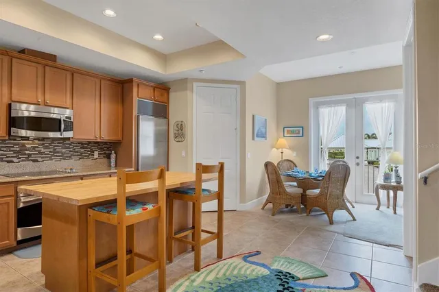 a kitchen with stainless steel appliances kitchen island granite countertop dining table chairs and a refrigerator