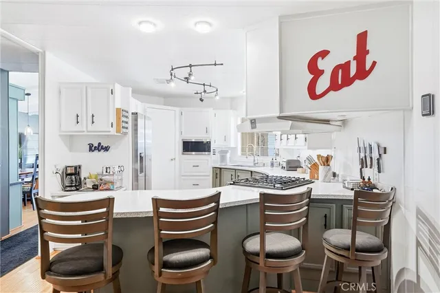 a kitchen with stainless steel appliances kitchen island granite countertop a stove a refrigerator and white appliances with wooden floor