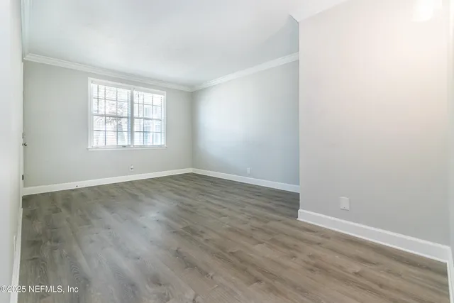 an empty room with wooden floor and window