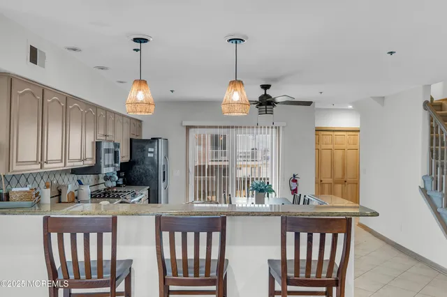 a kitchen with granite countertop a stove a sink dishwasher a dining table and chairs with wooden floor