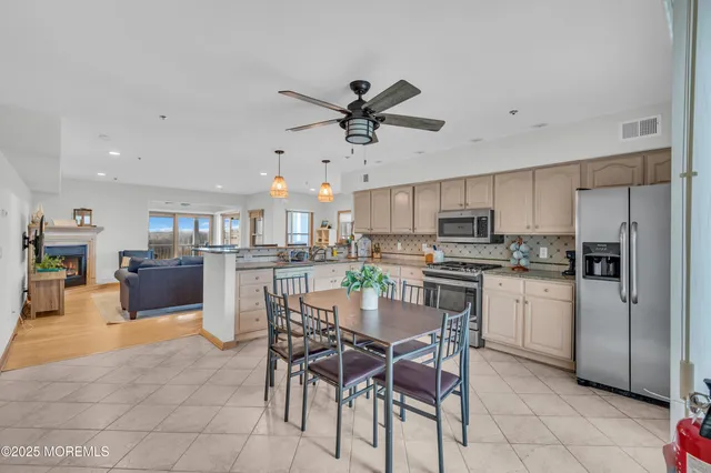 a kitchen with stainless steel appliances a refrigerator a stove a sink a dining table and chairs