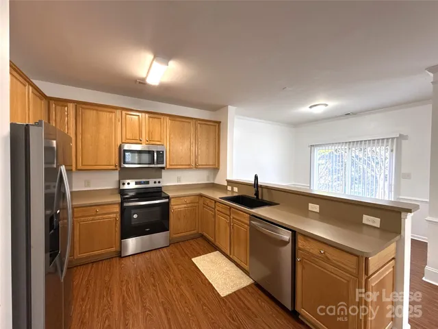 a kitchen with granite countertop a sink stove refrigerator and wooden cabinets