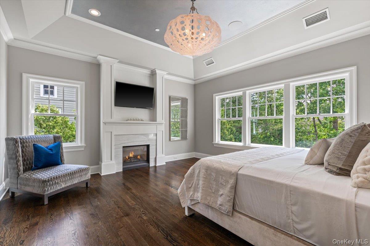 81 Wappanocca Avenue Rye, NY 10580 - Photo 11 of 27 Bedroom featuring wood finished floors, a lit fireplace, ornamental molding, a raised ceiling, and recessed lighting