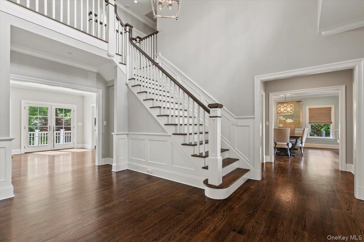 81 Wappanocca Avenue Rye, NY 10580 - Photo 2 of 27 Staircase featuring a chandelier, wood finished floors, crown molding, and a towering ceiling
