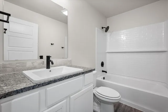 a bathroom with a granite countertop sink toilet and a mirror