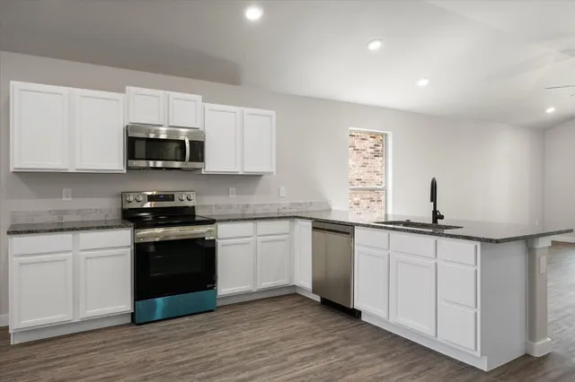 a kitchen with sink a microwave and cabinets