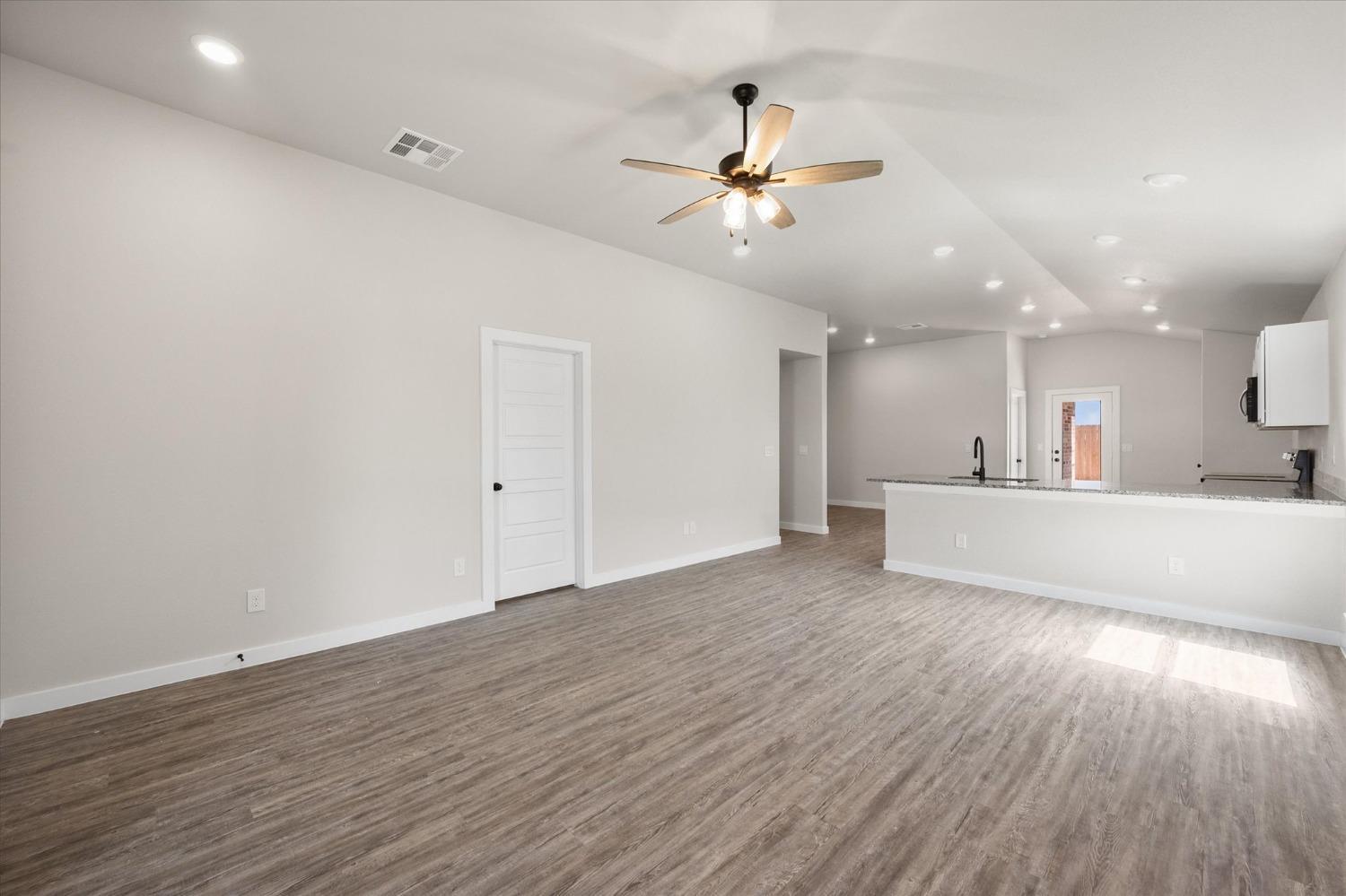 8622 26th Street Lubbock, TX 79407 - Photo 10 of 16 a view of an empty room with wooden floor and a ceiling fan