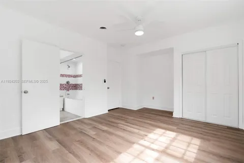 a view of a room with a bed and wooden floor