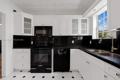 a kitchen with granite countertop a sink a stove and cabinets