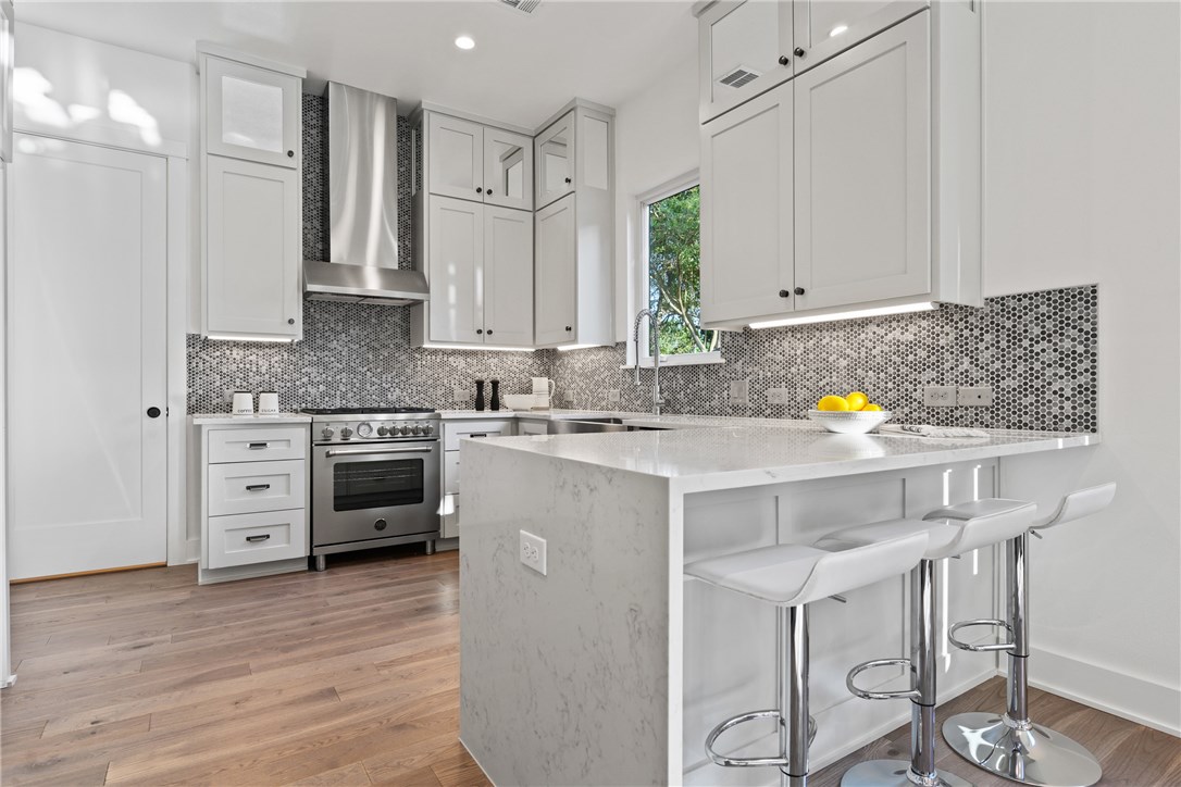 a kitchen with stainless steel appliances a stove a sink cabinets and a wooden floor