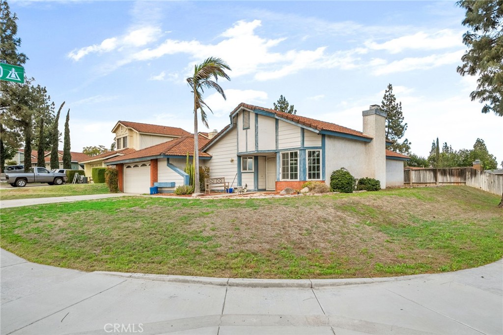 a view of a white house with a yard plants and large tree