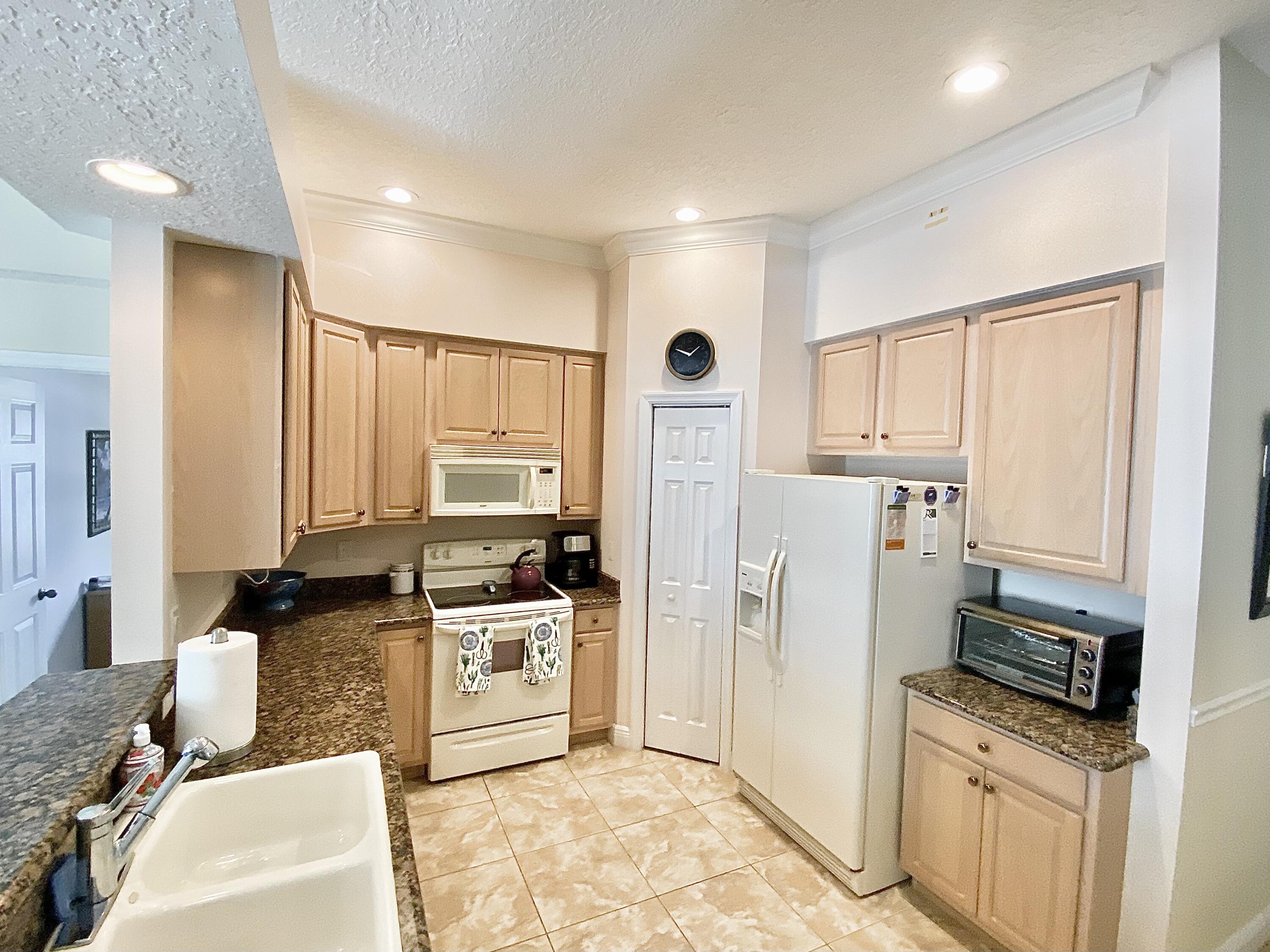 225 Clocktower Drive Jupiter, FL 33458 - Photo 8 of 40 a kitchen with stainless steel appliances granite countertop a refrigerator a stove a sink and white cabinets with wooden floor