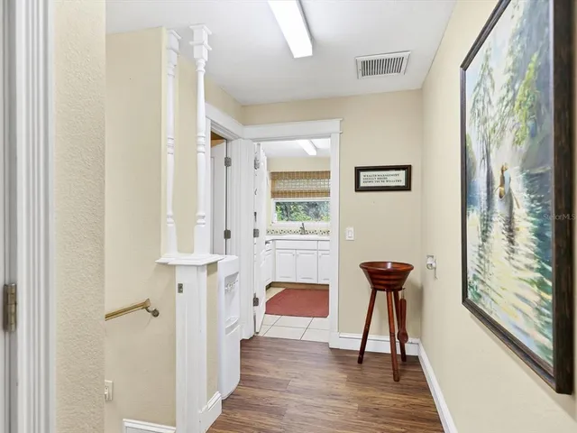 a kitchen with stainless steel appliances kitchen island granite countertop a stove a refrigerator a oven a dining table and chairs with wooden floor