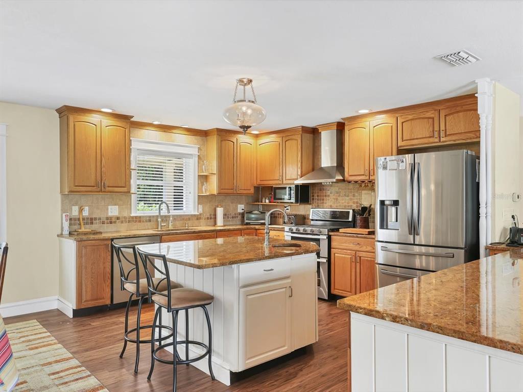 4708 Hidden River Road Sarasota, FL 34240 - Photo 20 of 67 a kitchen with stainless steel appliances granite countertop a refrigerator a sink a stove and white cabinets with wooden floor