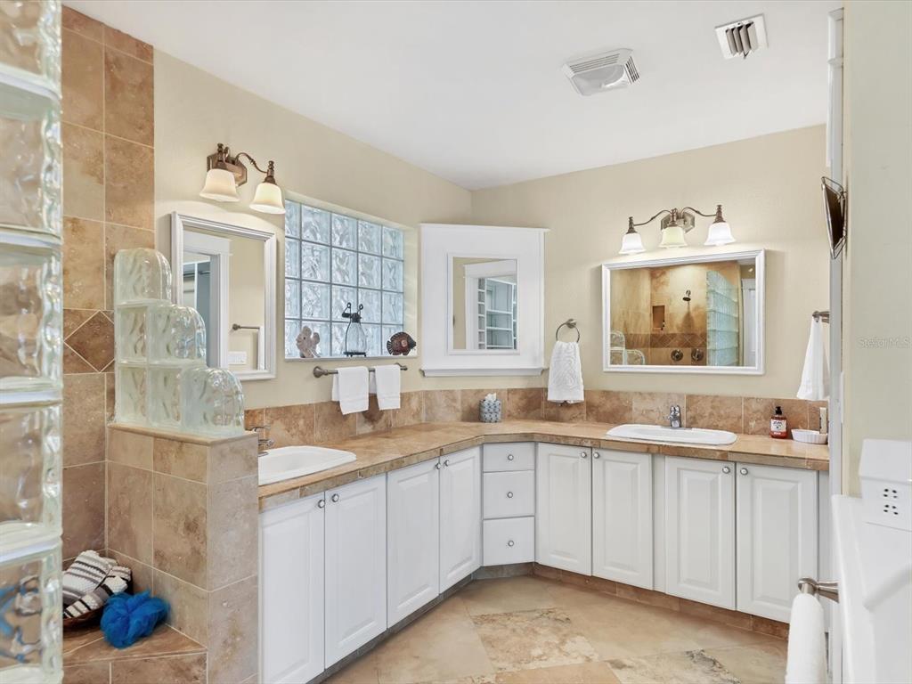 4708 Hidden River Road Sarasota, FL 34240 - Photo 23 of 67 a view of double vanity sink a mirror a window and a lamp