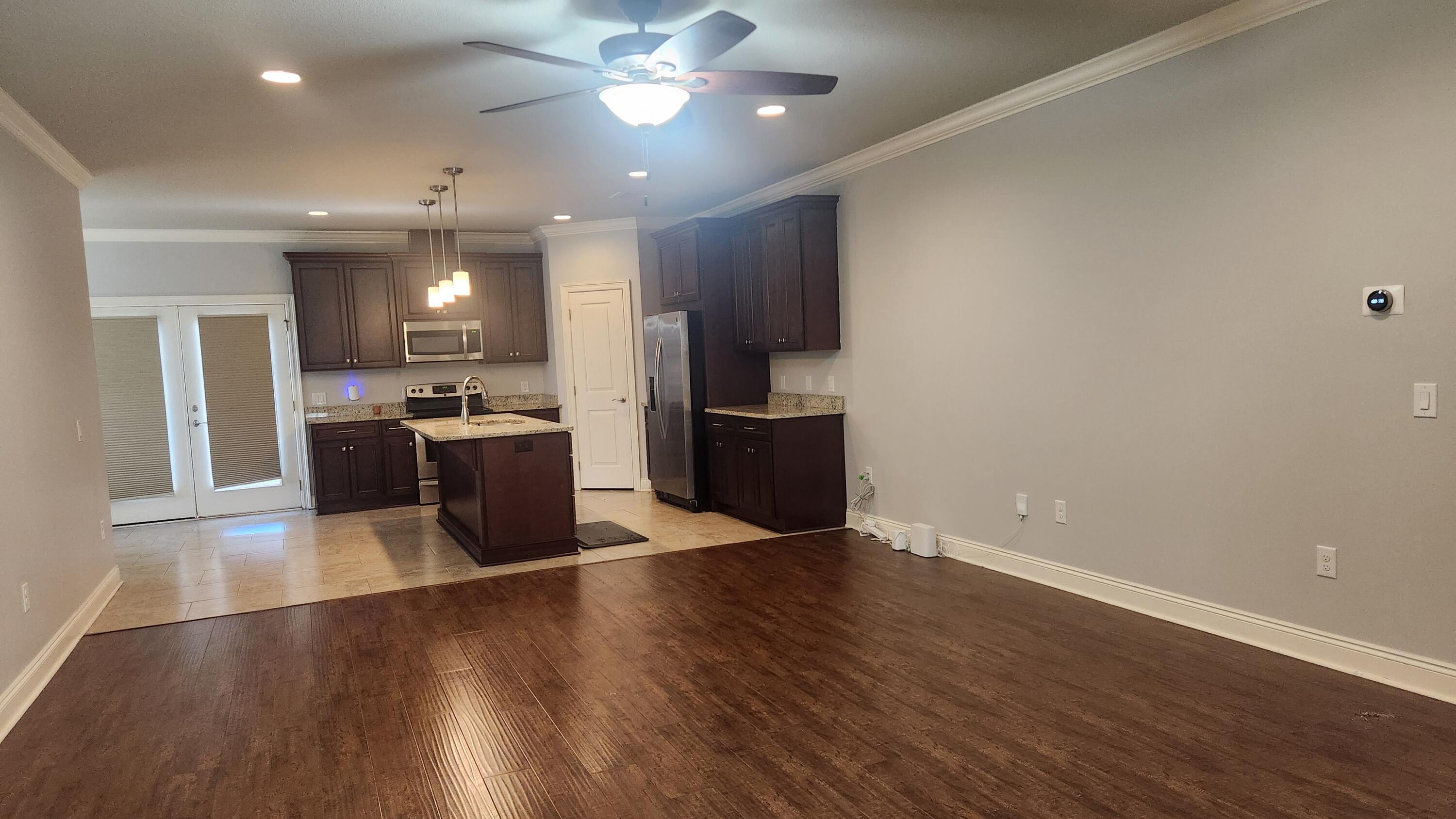 2133 Janet Street Navarre, FL 32566 - Photo 2 of 14 an empty room with wooden floor and kitchen view