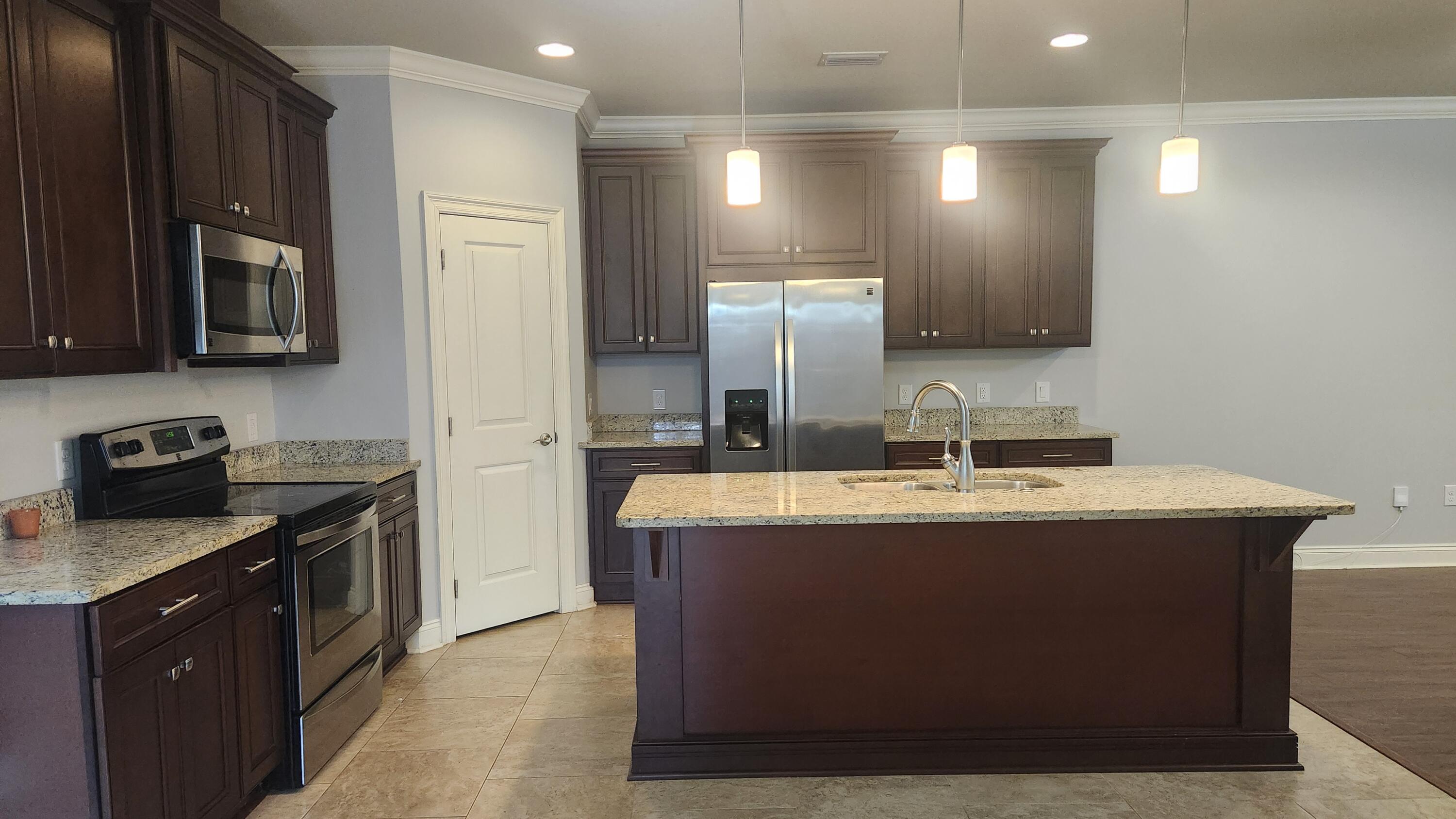 2133 Janet Street Navarre, FL 32566 - Photo 4 of 14 a kitchen with kitchen island granite countertop a sink stove and refrigerator