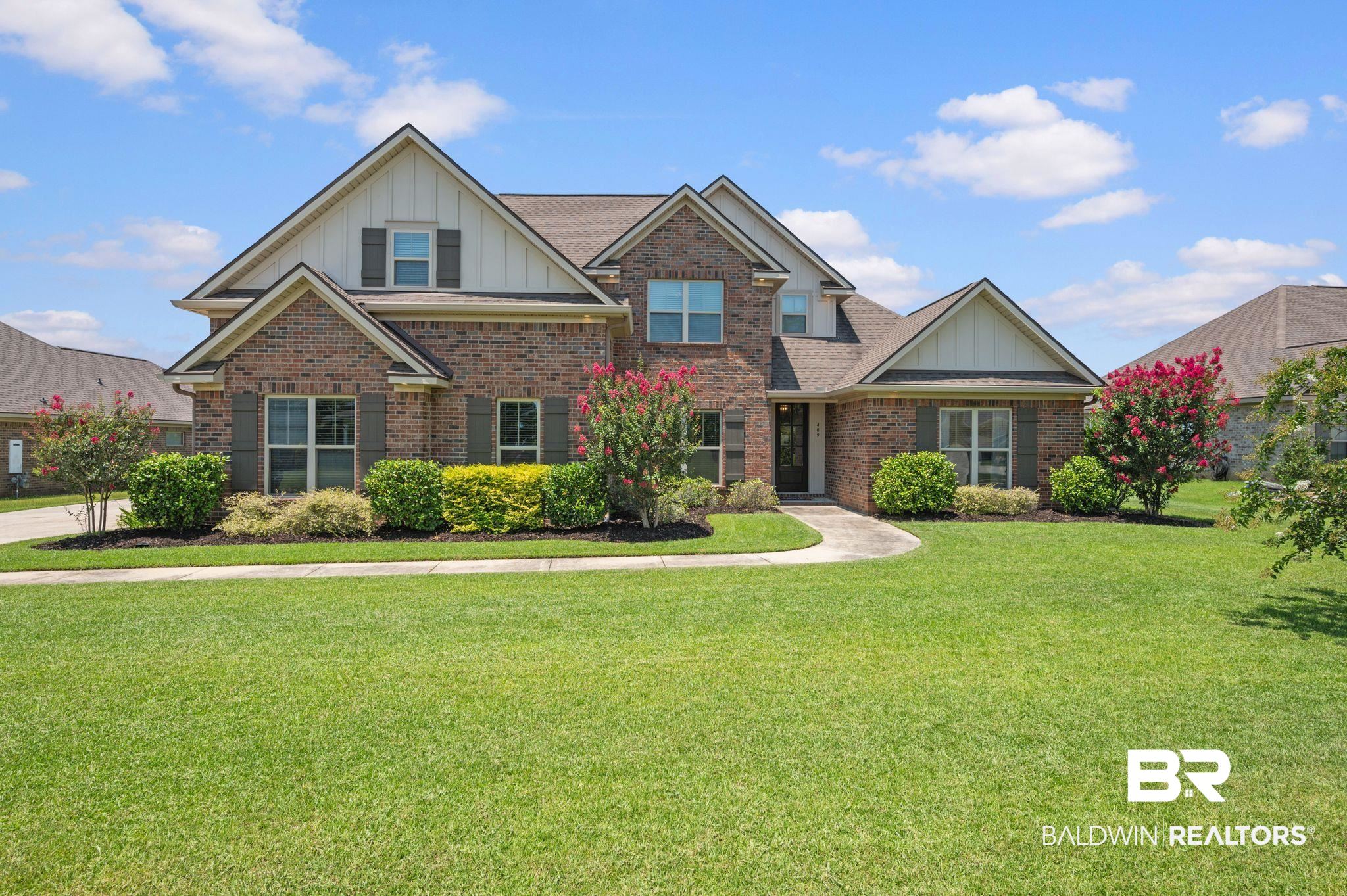 Traditional brick residence featuring a prominent gabled roofline, dark shutters, and a well-maintained front lawn