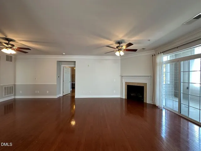 a view of an empty room with wooden floor and a fireplace