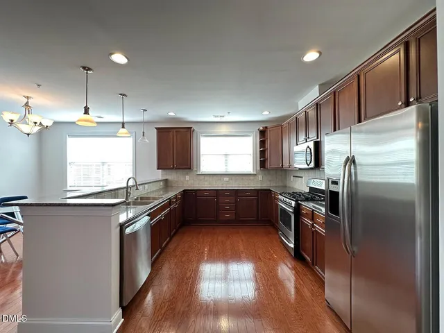 a kitchen with granite countertop stainless steel appliances cabinets a sink and a counter top space
