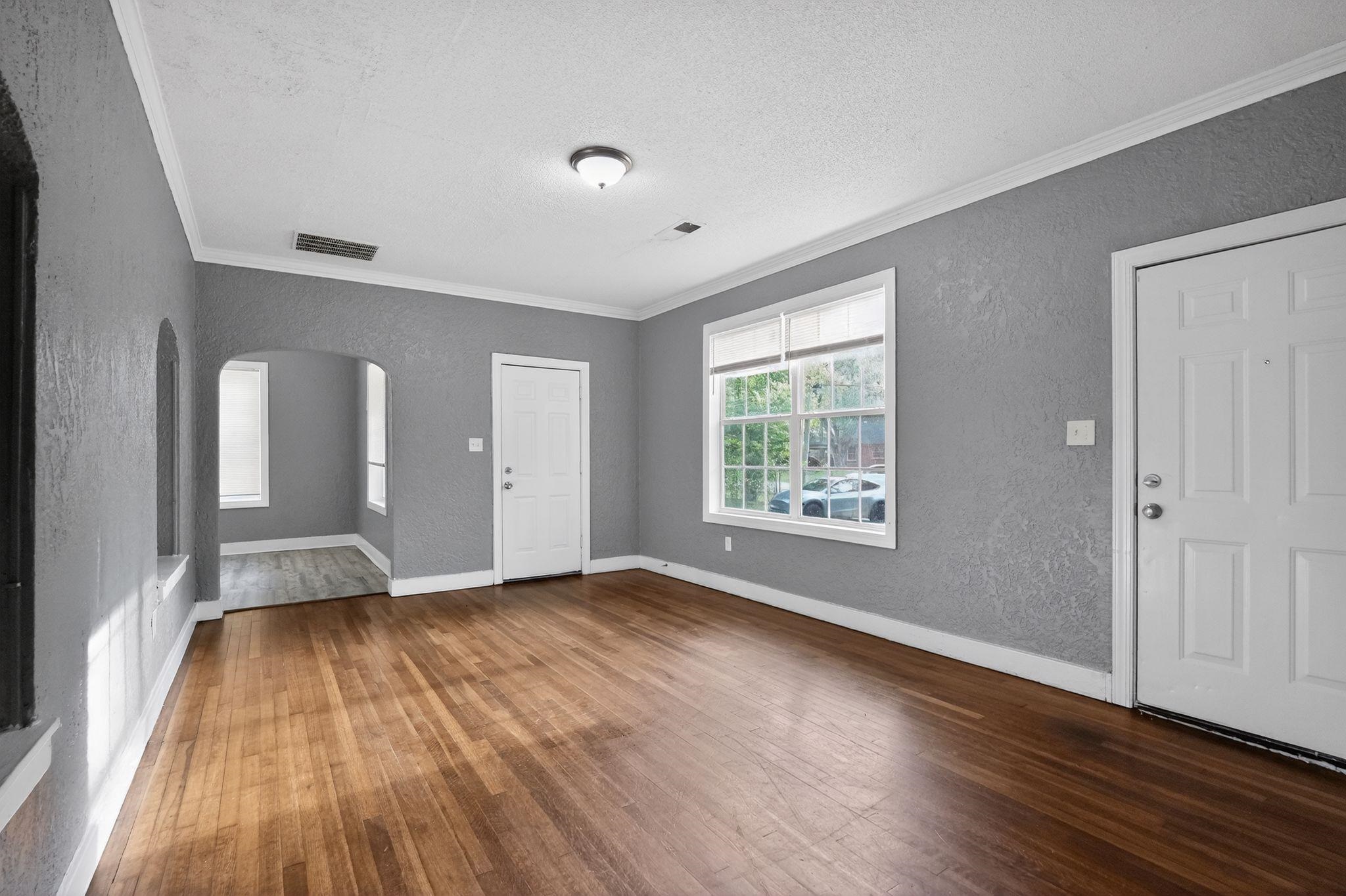 4199 Auburn Road Memphis, TN 38116 - Photo 8 of 32 Spacious room featuring wood-finish flooring, textured wall finish, crown molding, a multi-pane window with blinds, and white trim