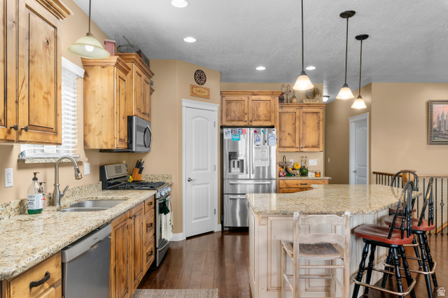 5702 950 North Ogden, UT 84404 - Photo 19 of 36 Kitchen featuring wood-finish cabinetry, granite countertops, stainless steel appliances, a kitchen island with pendant lighting, and dark wood-finish flooring