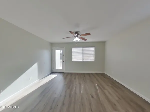 a view of an empty room with wooden floor and a window