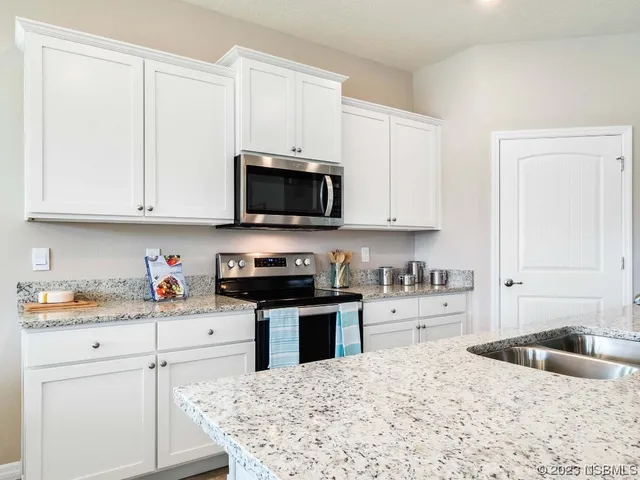 a living room with stainless steel appliances kitchen island granite countertop a couch a dining table and chairs