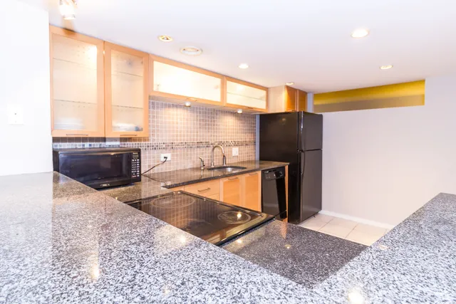 a kitchen with stainless steel appliances granite countertop a refrigerator a sink and a stove