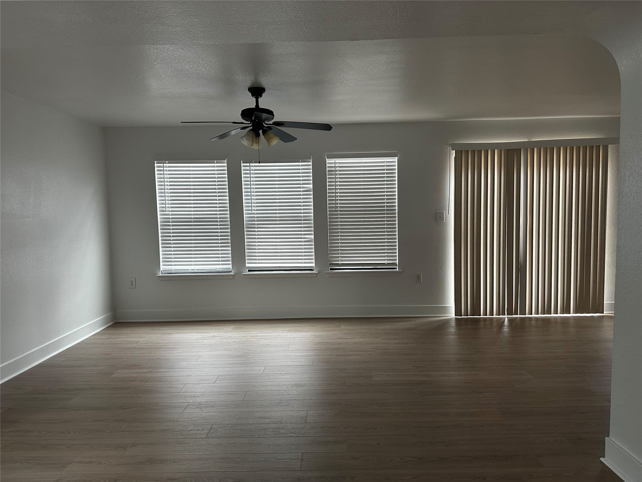 8016 Bannock Lane Austin, TX 78747 - Photo 11 of 32 an empty room with wooden floor chandelier fan and windows