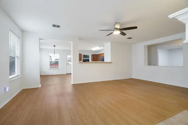a view of an empty room with window and wooden floor