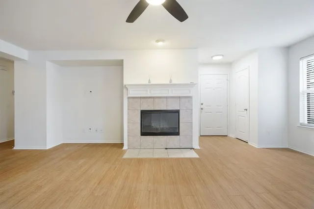 a view of an empty room with wooden floor and a fireplace