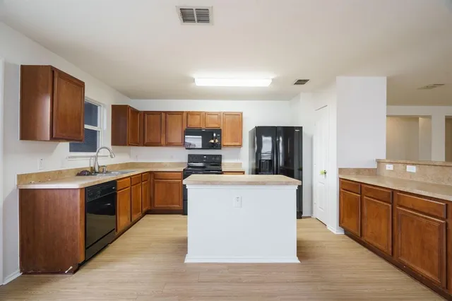 a large kitchen with stainless steel appliances wooden cabinets and a sink